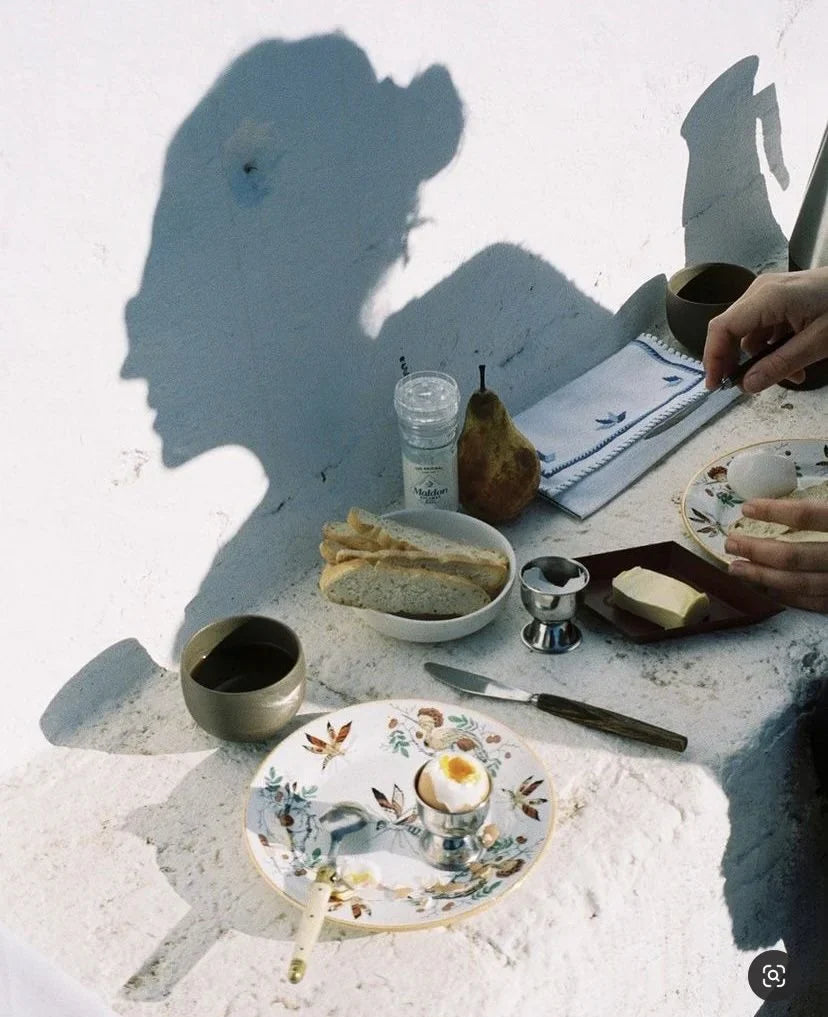 Quiet Mediterranean morning — espresso on a marble café counter, sunlight through a shutter, no person in frame